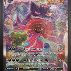 Può includere: Carta Pokémon olografica Gengar VMAX. La carta presenta un grande Gengar viola con un corpo rosso e rosa, circondato da uno sfondo vorticoso e colorato. Il testo include "Fear and Panic" e "G-Max Swallow Up".