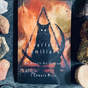 May include: A book titled "Fearless Familiars" with a black cat illustration on the cover. The cover has a dark orange and black background with the words "An Oracle Guidebook" and the author's name, J Edward Neill.