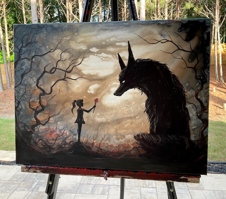 May include: An original painting on canvas depicts a dark, surreal scene. A young figure offers a flower to a large, shadowy wolf. The artwork features a muted color palette with a focus on the figures and the surrounding forest.