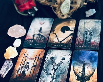 Puede incluir: Un juego de cartas de tarot con ilustraciones góticas de esqueletos. Las cartas presentan títulos como "The Fool", "Page of Bones" y "The Hierophant". Las cartas están dispuestas sobre una superficie oscura, junto con cristales y elementos decorativos.