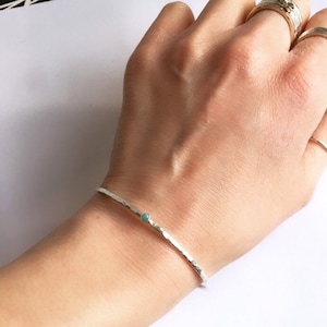 May include: A silver hammered bangle bracelet with a small turquoise gemstone accent.
