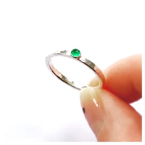 May include: A silver ring with a hammered texture and a small green gemstone set in the centre.