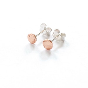 May include: A pair of silver stud earrings with a small, round, textured copper disc on each earring.
