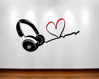 May include: Black headphones with a red heart drawn on a white wall. The headphones are connected to the heart by a black line.