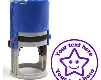 Könnte beinhalten: Ein blauer Stempel mit selbsttintendem Stempelkissen und einem transparenten Plastikdeckel. Der Stempel zeigt einen lila Stern mit einem Smiley und dem Text "Your text here" um den Stern herum.