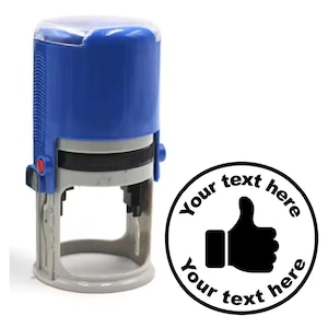 May include: A blue self-inking stamp with a clear plastic top. The stamp features a black thumbs up icon and the text "Your text here Your text here".