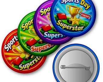 Könnte beinhalten: Eine Sammlung bunter „Sports Day Superstar“-Ansteckbuttons. Jeder Button zeigt eine goldene Trophäe, rote Sitzsäcke und das Wort „Finish“ auf einer Flagge. Die Buttons sind rot, grün, lila und blau mit weißem Text.