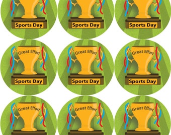 Könnte beinhalten: Neun runde Aufkleber mit einer goldenen Trophäe mit den Worten "Great Effort" und "Sports Day". Die Trophäe hat rote und blaue Bänder. Der Hintergrund ist grün mit weißen Streifen.