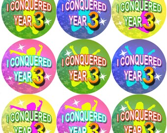 Könnte beinhalten: Neun bunte runde Aufkleber mit dem Text "I Conquered Year 3" in gelber, orangefarbener und roter Schrift. Jeder Aufkleber zeigt die Silhouette eines springenden Kindes mit erhobenen Armen vor einem Sternenhintergrund.