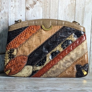Könnte beinhalten: Eine Vintage-Clutch aus braunem, schwarzem und orangefarbenem Schlangenleder. Die Clutch hat ein einzigartiges Patchwork-Design und einen goldfarbenen Verschluss.