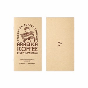 Op de afbeelding: Twee bruine papieren notitieboekjes met een bruin logo op de voorkant. Het logo is een cirkel met de tekst "Starbucks Coffee Company" en een tekening van een koffieplant. De tekst "Green Arabica Coffee Est. 1971 Seattle Washington" staat onder de cirkel. De tekst "Traveler's Company Exclusively for Starbucks Reserve" staat onder het logo. Het andere notitieboekje heeft drie koffiebonen gedrukt op de voorkant.
