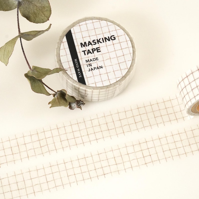 May include: A roll of white masking tape with a brown grid pattern. The tape is labeled "Masking Tape" and "Made in Japan".