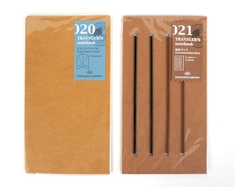 May include: Two Traveler's Notebook accessories: a kraft paper folder and a connecting rubber band set. The folder is labeled "020" and has a blue sticker with text. The rubber band set, labeled "021", includes black bands.