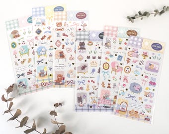 May include: Five sheets of colorful sticker paper with a checkered pattern. Each sheet features a different color scheme and cute illustrations of bears, cats, and rabbits. The stickers feature phrases like "I have a dream" and "Peace of mind".