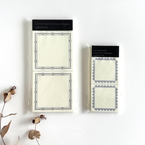Può includere: Due set di blocchi per appunti con stampa tipografica in confezione trasparente. I blocchi per appunti hanno uno sfondo color crema con un bordo quadrato grigio. La parte superiore della confezione riporta la scritta "LETTERPRESS PRINTING PROCESS" e un codice prodotto.