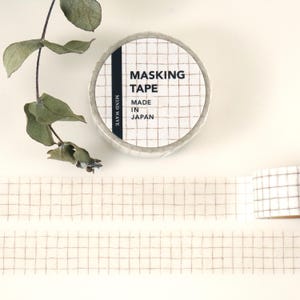May include: A roll of white washi tape with a brown grid pattern. The tape is labeled "Masking Tape" and "Made in Japan".