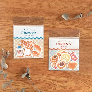 May include: Two clear plastic packets of paper stickers with bread illustrations. One packet has a blue wave design and the text "いつものパン". The other has a red wave design and the text "菓子パン". Stickers include bread, croissants, and milk.