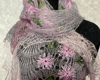 May include: A delicate, hand-knitted shawl in shades of lavender and gray, adorned with embroidered pink flowers and green leaves. The openwork design creates a lacy effect, perfect for adding a touch of elegance to any outfit.