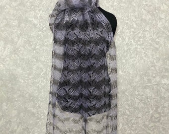 May include: A delicate, hand-knitted shawl in shades of gray and purple. The shawl is made of a lightweight, airy yarn and features a delicate lace pattern.