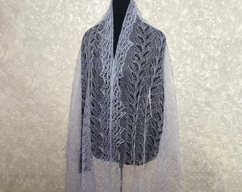 May include: A delicate, light purple lace shawl with a floral pattern. The shawl is draped over a mannequin and has a flowing, ethereal look.