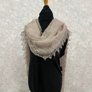 Peut inclure: Un châle délicat de couleur beige clair avec une bordure en dentelle. Le châle est drapé sur un mannequin noir.