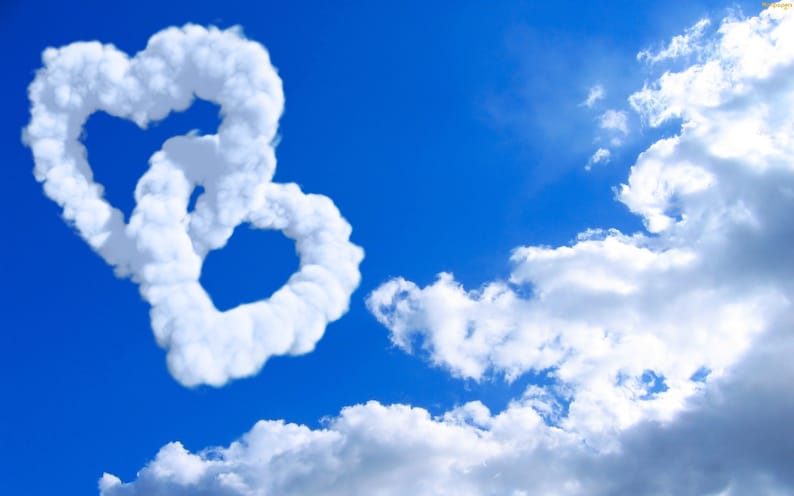 May include: Two white heart-shaped clouds in a bright blue sky. The clouds are intertwined, creating a romantic and whimsical scene.
