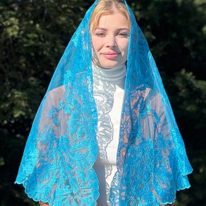 May include: A turquoise lace mantilla with floral embroidery. The mantilla is sheer and delicate, with a scalloped edge.