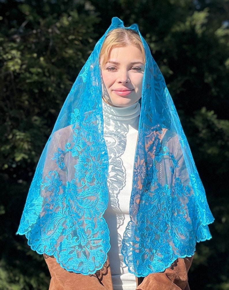 May include: A turquoise lace mantilla with floral embroidery. The mantilla is sheer and delicate, with a scalloped edge.