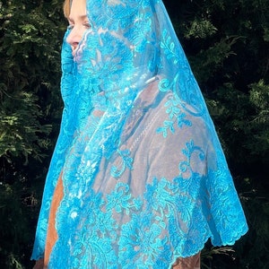 May include: A light blue lace veil with a floral pattern. The veil is sheer and delicate, with a scalloped edge.