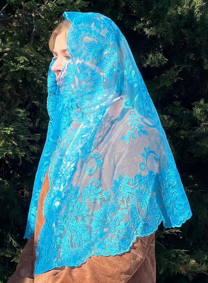 May include: A light blue lace veil with a floral pattern. The veil is sheer and delicate, with a scalloped edge.