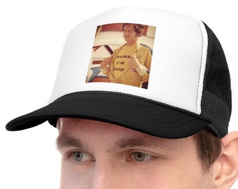 Peut inclure: Une casquette de camionneur noire et blanche avec un panneau avant blanc représentant une photo d'une personne portant un t-shirt jaune avec le texte "Damn, I'm good." imprimé dessus.