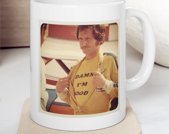 Peut inclure: Une tasse en céramique blanche avec une photo d'un homme portant un t-shirt jaune sur lequel est imprimé le texte "DAMN I'M GOOD". L'homme sourit et tient son t-shirt ouvert pour révéler le texte.