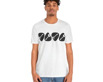 Peut inclure: T-shirt blanc avec un motif noir de quatre médiators de guitare avec des silhouettes de guitare à l'intérieur de chaque médiator.