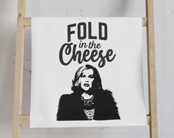 Peut inclure: Une serviette de cuisine blanche avec du texte noir qui dit "FOLD in the Cheese" et une illustration en noir et blanc d'une femme aux cheveux longs.