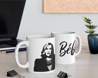 Peut inclure: Deux tasses en céramique blanche avec des motifs noirs. Une tasse présente une silhouette noire et blanche d'une femme avec le texte "Bébé" sur l'autre tasse.
