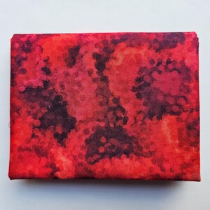 Op de afbeelding: Een rechthoekig canvas met een abstract ontwerp in tinten rood, karmozijnrood en zwart. Het kunstwerk heeft een textuur. Het canvas is gespannen en klaar om te worden tentoongesteld, geschikt voor interieurdecoratie.