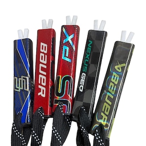 May include: Five hockey stick blade tape with different designs and colors. The tape is black with white stitching and has a loop at the end. The tape is attached to a hockey stick blade with the brand name printed on it. The brands are Bauer, Nexus Geo, and FX.