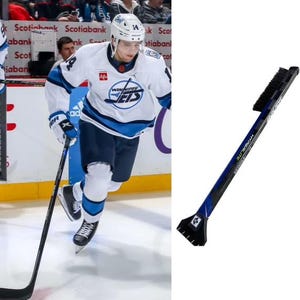 May include: A hockey player wearing a white and blue jersey with the text "Winnipeg Jets" on the front, skates on the ice with a hockey stick. A blue and black ice scraper with a brush is shown on the right side of the image.
