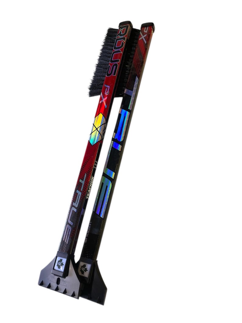 May include: Two hockey stick ice scrapers with black brushes and a black plastic scraper at the bottom. The sticks are red and black with the text "TRUE" and "STX" on them.