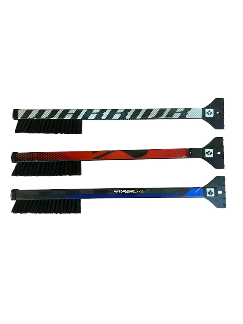 May include: Three ice scrapers with brushes. The scrapers are black with different colored designs. The first is black and white, the second is red and black, and the third is blue and black. The scrapers have a brush on one end and a scraper on the other.
