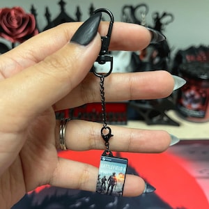 May include: Black metal keychain with a small rectangular charm featuring the "Battlefield 6" game cover art. The keychain has a lobster clasp and a short chain. The game cover art shows soldiers in a war scene.