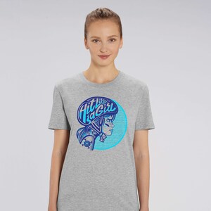 K&ouml;nnte beinhalten: Graues T-Shirt mit einem blauen und wei&szlig;en Grafikdruck einer Frau mit Helm und dem Text "Hit like a Girl".