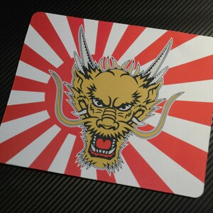 May include: A rectangular mousepad featuring a golden dragon head with an open mouth, set against a red and white sunburst design. The dragon has detailed features and a fierce expression. The mousepad is likely made of a smooth material.