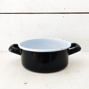 May include: A black enamel saucepan with white enamel lining and two handles.