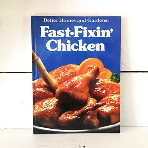 May include: A cookbook titled "Fast-Fixin' Chicken" by Better Homes and Gardens. The cover features a vibrant image of cooked chicken pieces with orange slices. The title is in white letters on a blue background.