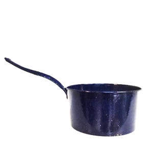Puede incluir: Una cacerola de esmalte azul marino con un mango largo. La pequeña olla tiene un cuerpo redondeado y un mango azul oscuro que se extiende desde el lateral. La cacerola está sobre un fondo blanco.