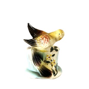 May include: A white ceramic mug with a black handle and the text "But First, Coffee" in a bold, black font. The mug sits on a white surface, showcasing its clean design.