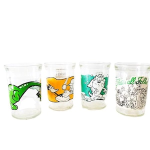Könnte beinhalten: Vier klare Glastrinkbecher mit farbenfrohen Looney Tunes-Charaktergrafiken. Die Gläser zeigen verschiedene animierte Figuren, darunter einen grünen Dinosaurier, einen Baseballspieler, ein weißes Wesen und eine Gruppe mit dem Text That's all Folks.