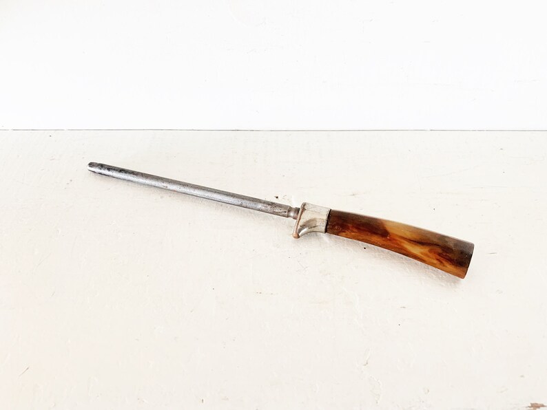 May include: A silver steel knife sharpener with a brown wooden handle.
