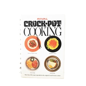 May include: A vintage cookbook titled "RIVAL CROCK-POT COOKING" with a white cover. The cover features the title in bold black letters and images of prepared dishes. The cookbook includes recipes for savory pepper steak, spaghetti sauce, Swiss steak, and cheesecake.
